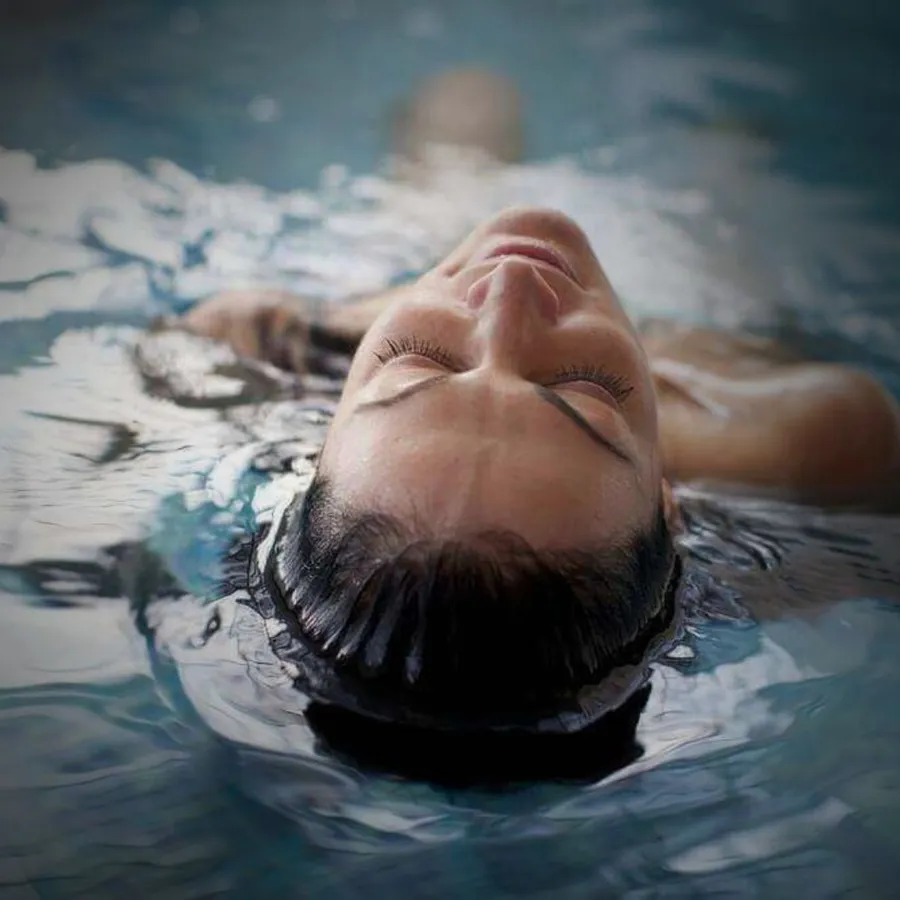 Woman floating face-up in still water with her eyes closed